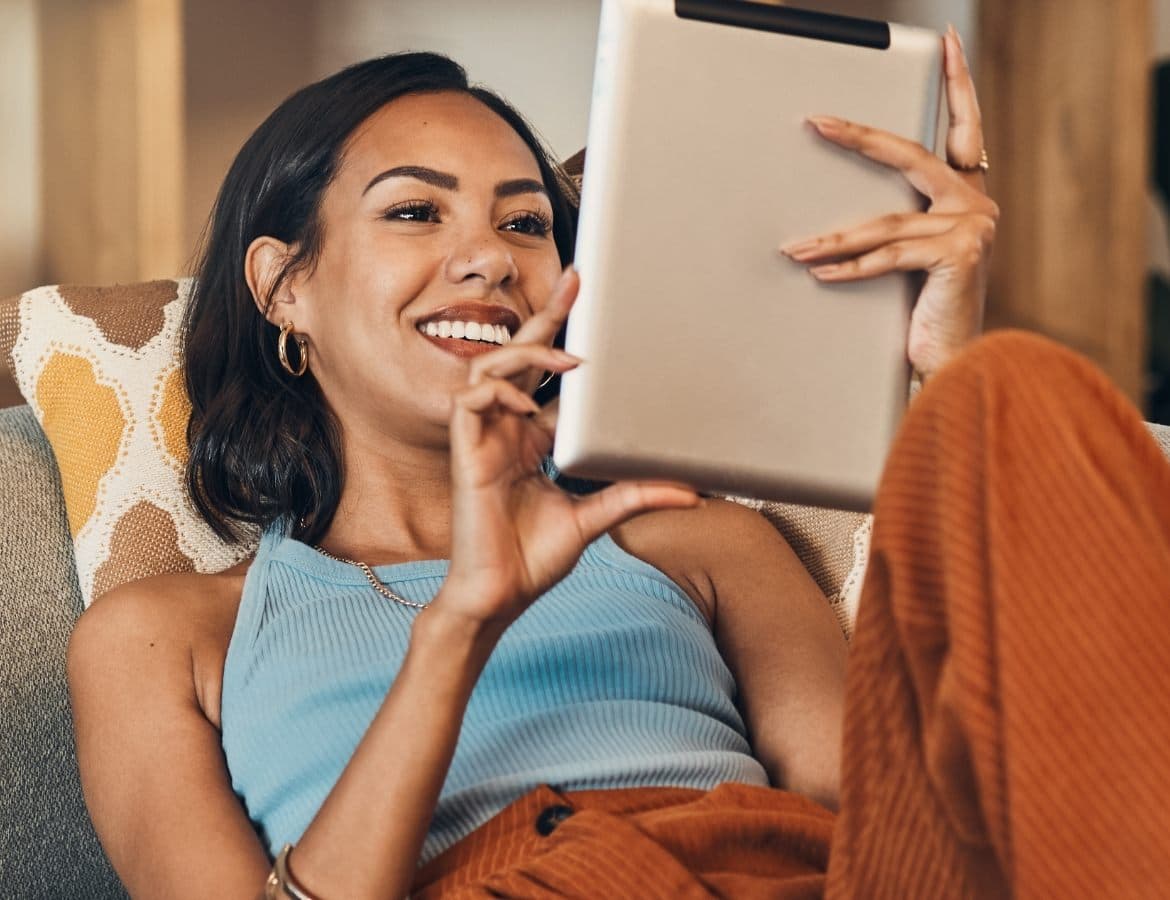 Woman laying on the couch browsing on her tablet