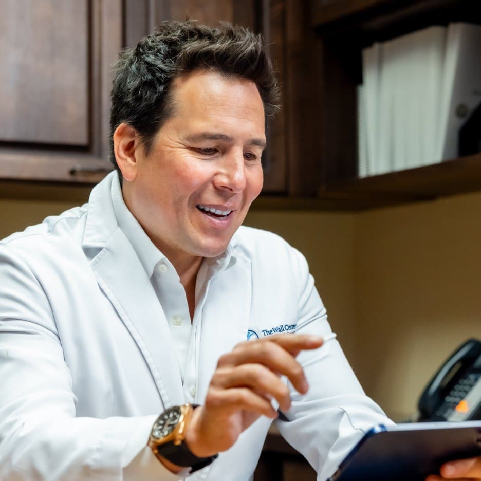 Simeon Wall Jr., MD, FACS reviewing information on a tablet in his office.