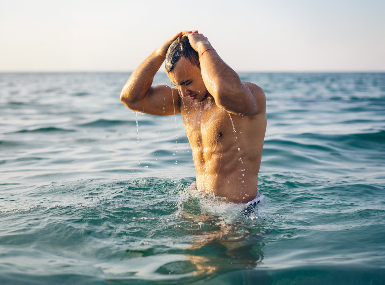 Man slicking hair back in ocean