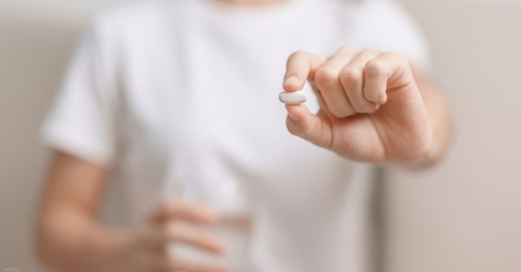 Model holding an acetaminophen pill