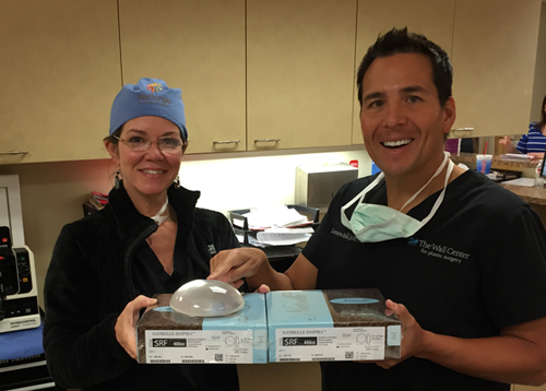 Dr. Holly Casey Wall and Dr. Simeon Wall Jr smiling and holding breast implants