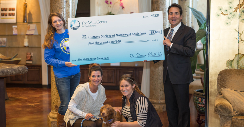 Dr. Simeon Wall Jr handing oversized $5,000 check to Humane Society of Northwest Louisiana workers