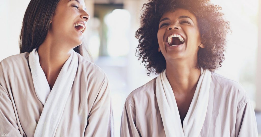 2 women in spa robes sharing a laugh