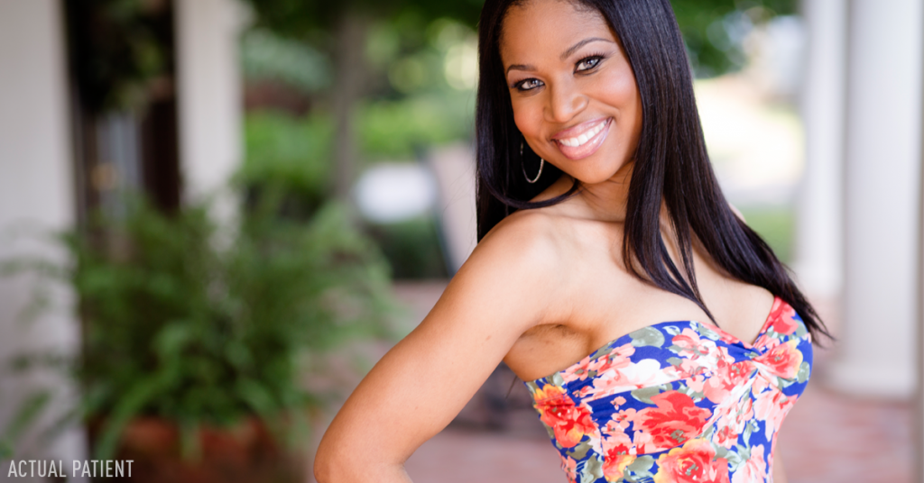 Attractive dark haired woman smiling at camera wearing print blouse