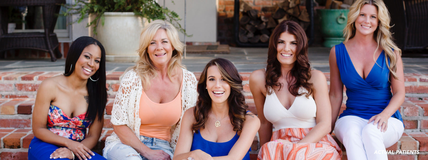 5 smiling women sitting together looking at the camera 