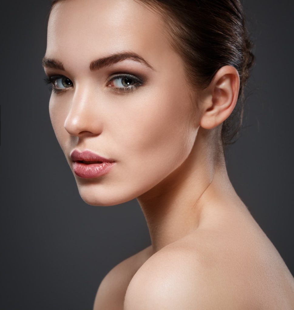 Woman with hair pulled back and smoky eye makeup, highlighting sculpted cheekbones and a refined nose profile