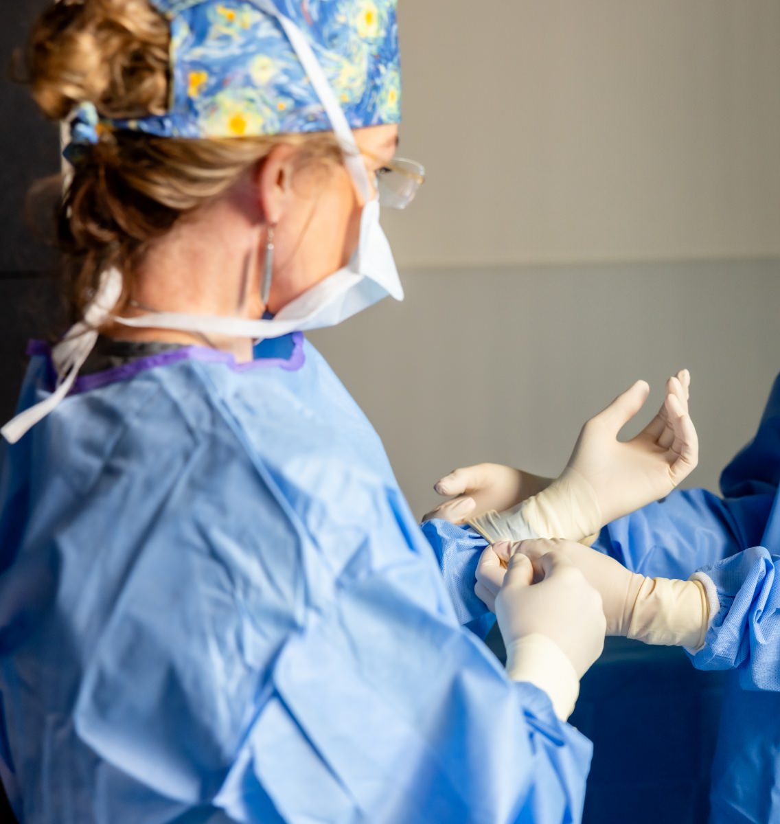 Dr. Holly Casey Wall having sterile surgical gloves being placed on