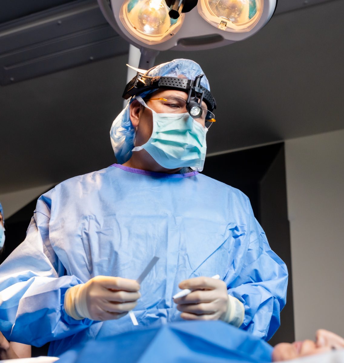 Dr. Simeon Wall Jr. wearing surgical garb, operating on a patient