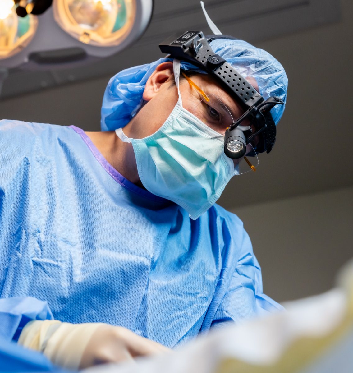 Dr. Simeon Wall Jr. wearing surgical garb, operating on a patient