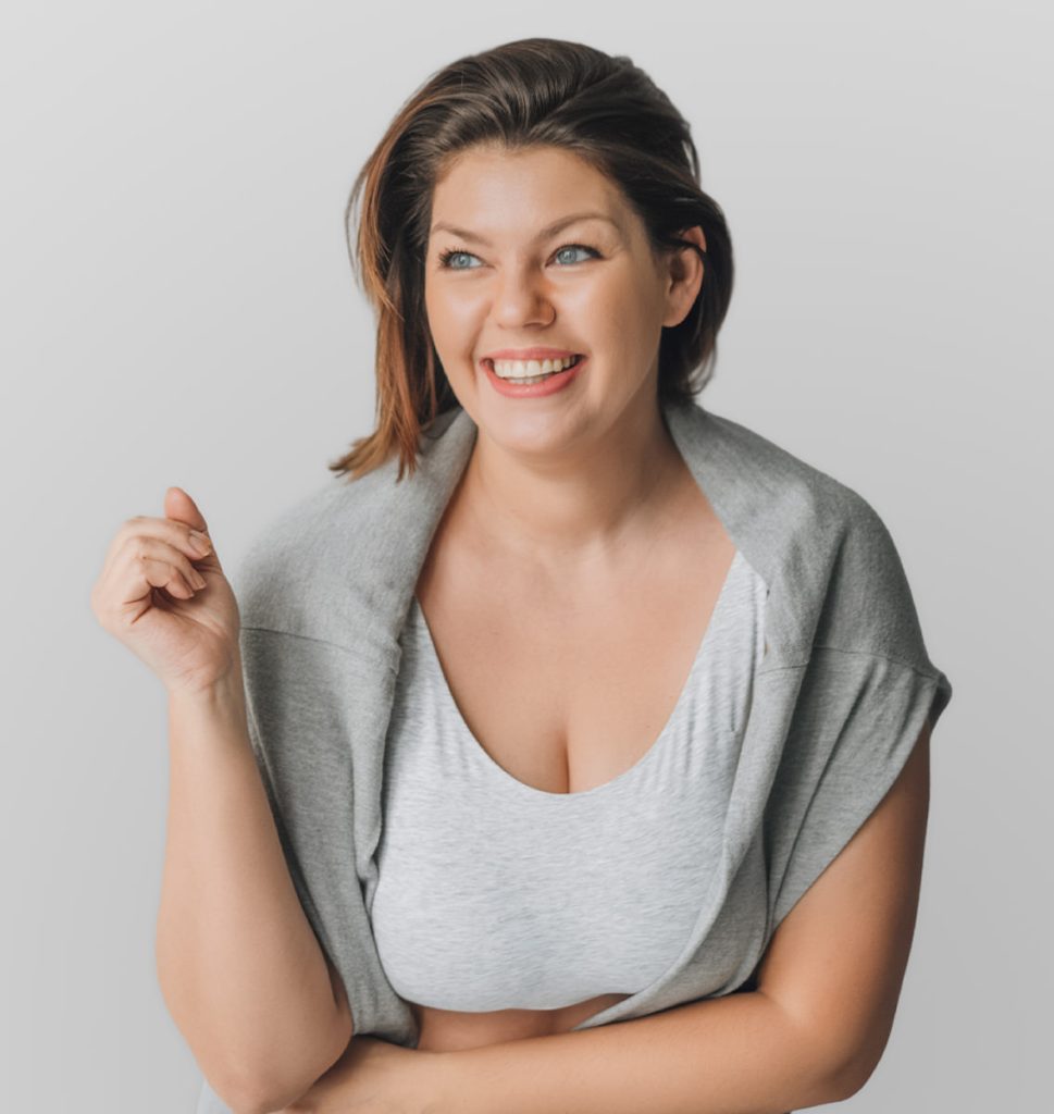 Smiling woman with short brown hair wearing a gray top and cardigan against a light background